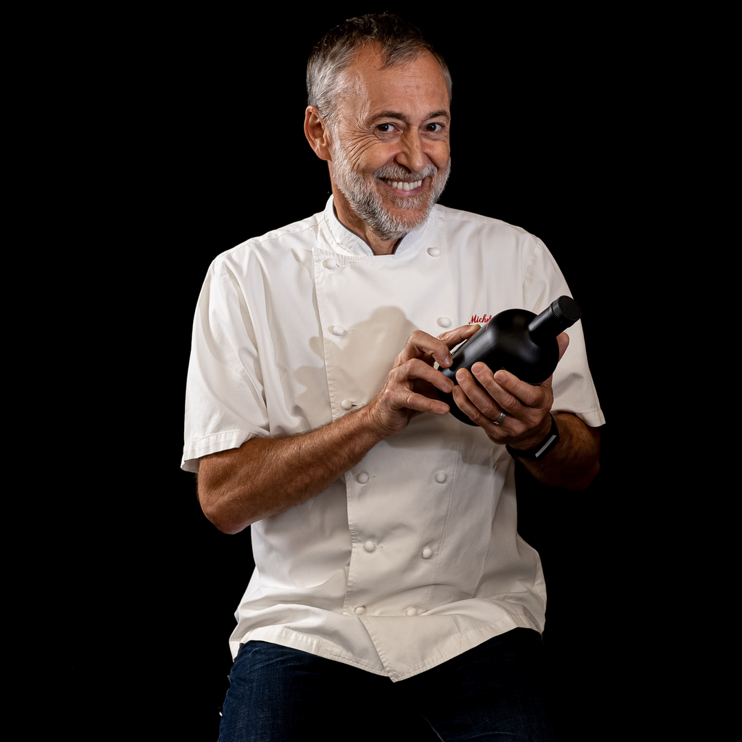 Michel Roux Jr holding Le Gavroche Gin at Nelson's Distillery & School