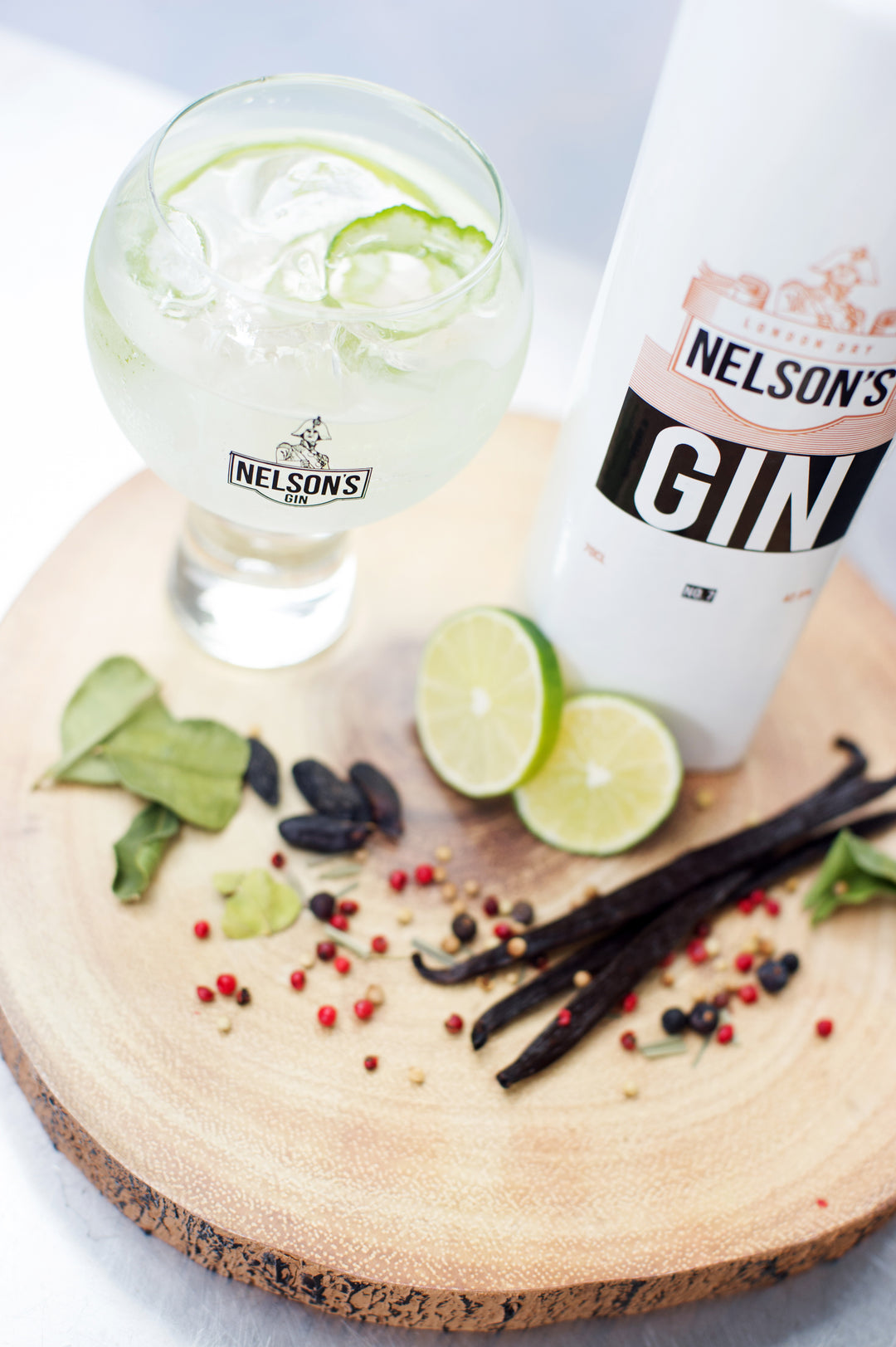 Nelson's 70cl ceramic London Dry bottle next to gin & tonic with lime peel garnish.