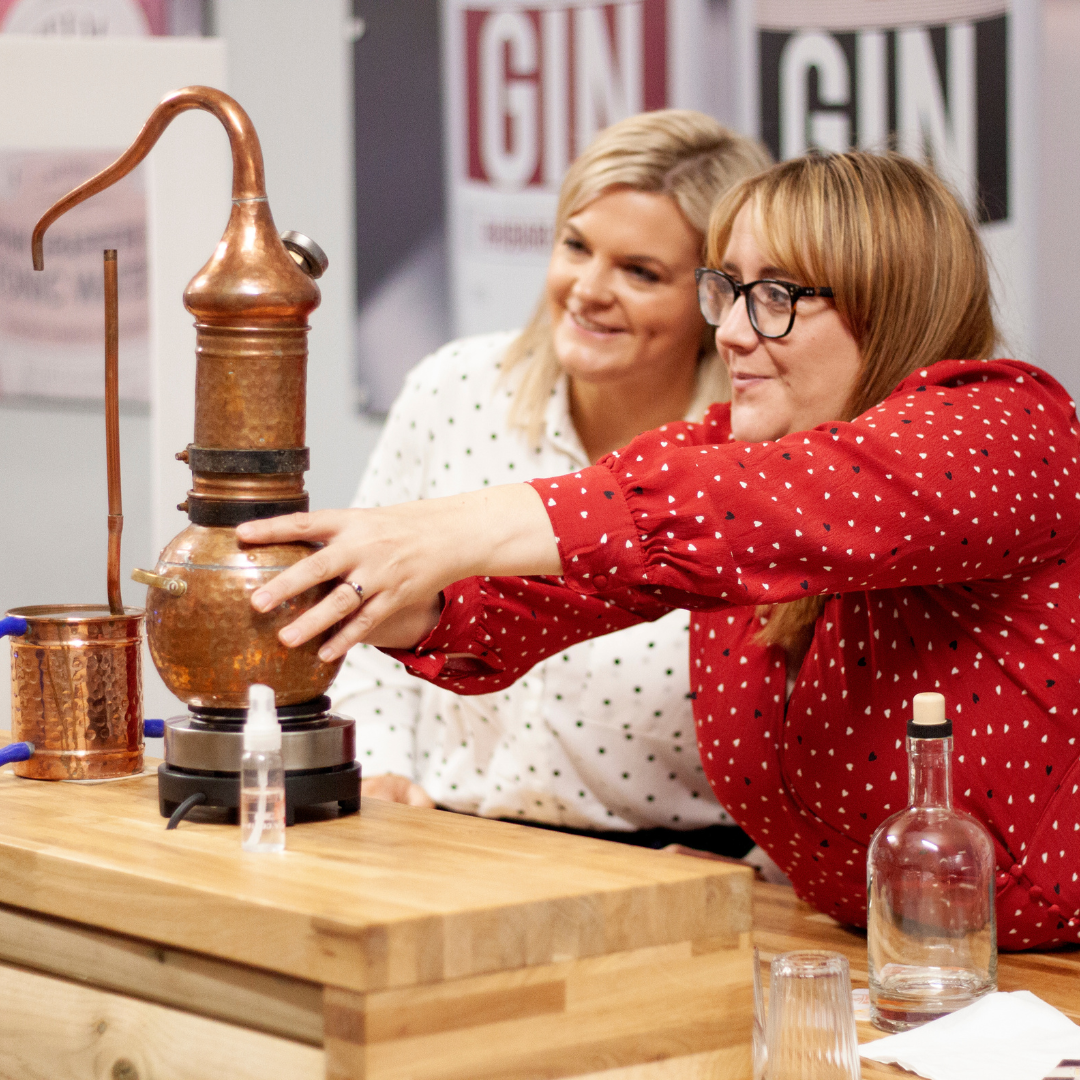 Two women placing a micro still on heater at Nelson's Gin, Vodka & Rum School