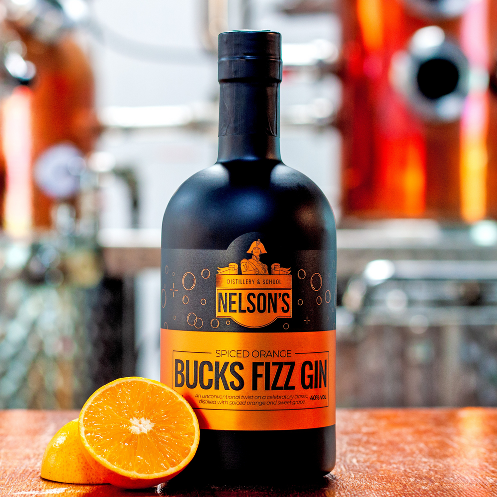Nelson's Bucks Fizz Gin with oranges by left hand side in front of blurred background of Nelson's 150L Alembic Still, Victory.